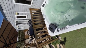 A hot tub on a deck with a wooden ladder, a table, and chairs. - Mobile home AC, pets allowed - 6 guests (Cessenon-sur-Orb)