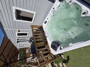 Boblebad på en terrasse med en træstige, et bord og stole.
