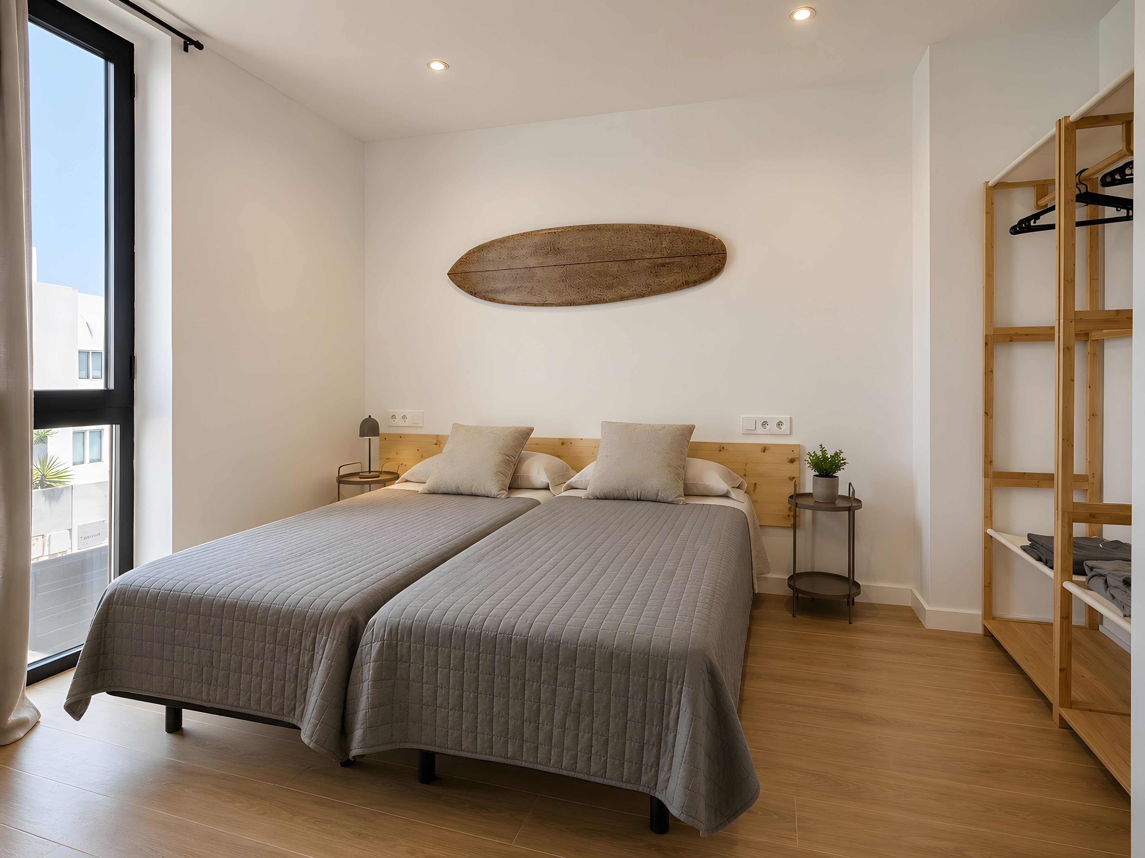 Un lit double avec une tête de lit, des tables de chevet, une étagère fixée au mur et un plancher en bois.