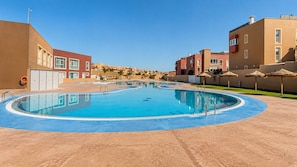 Una piscina con borde azul, rodeada de edificios con un estilo arquitectónico uniforme.