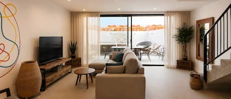 A modern living room with a sofa, TV, and a dining area with chairs and a table.