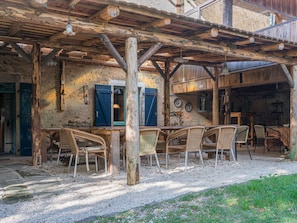 An outdoor wooden structure with a table and chairs, a rustic interior with a wooden ceiling, and a stone wall.