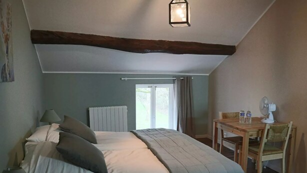 A bedroom with a bed, bedside table, chair, and a window with curtains. - Comfortable Family Room with Breakfast at the Farm (Grandrupt-de-Bains)