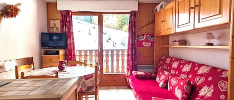 Una habitación acogedora con una mesa de comedor de madera, un sofá y un televisor.