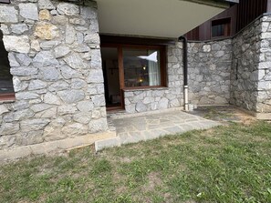 A stone building with a stone exterior, a wooden door, and a small porch area. - Ground floor apartment - pets welcome - 4 guests (Valmorel)