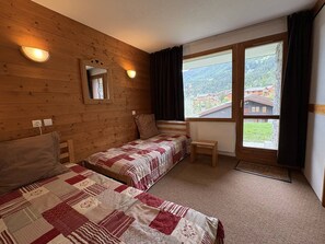 A room with two beds, a window with a view, and a mirror on the wall.