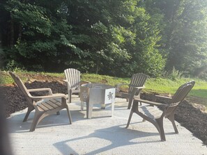 Area esterna con sedute in stile Adirondack e un tavolo centrale, circondata da alberi.