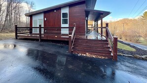 Une cabane en bois dotée d’un porche et d’un escalier menant à un garage.