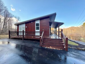 Una baita di legno con un portico e una scala che conduce a un garage.