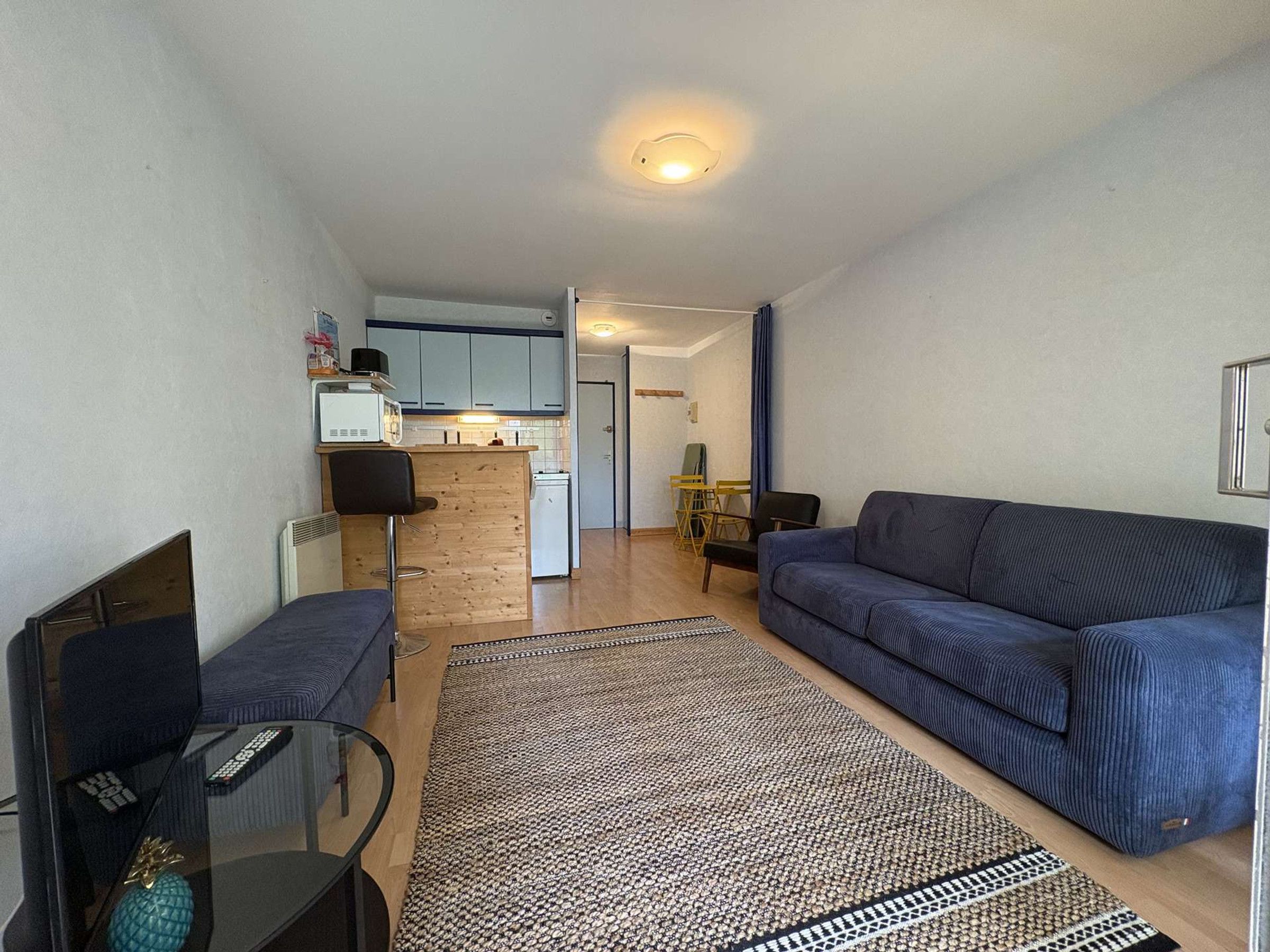 Ein gemütlicher Wohnbereich mit einer Couch, einem kleinen Tisch und einer Küchenzeile im Hintergrund.