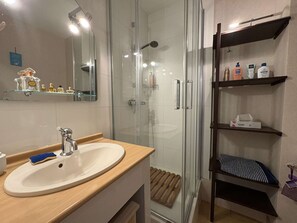 Un bagno moderno con box doccia in vetro, mobile lavabo in legno e ripiano con articoli da toilette.