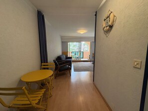 Ein Flur mit Esstisch und Stühlen, einer Couch und Blick auf einen Außenbereich mit einem Balkon.