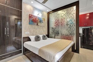 Un dormitorio con cama, armario, panel decorativo en la pared y zona de cocina.