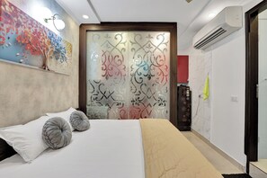 A bedroom with a bed, pillows, a decorative wall, a sliding door with intricate patterns, and an air conditioning unit. - Welcome to Lutyens Imperial, a spacious and thoughtfully designed apartment (New Delhi)