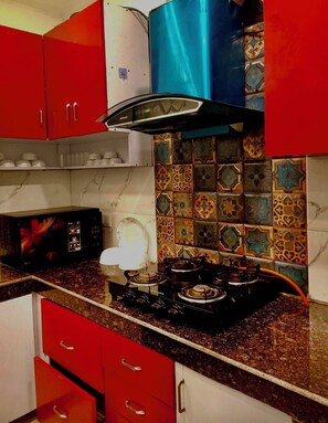 Una cocina con armarios rojos, un microondas, una estufa y una campana extractora azul.