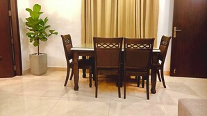 A dining area with a table and chairs, a potted plant, and a closed door.