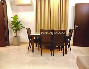 A dining area with a table and chairs, a potted plant, and a closed door.