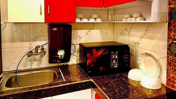 A kitchen with a sink, a microwave, and red cabinets.