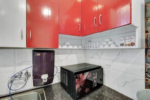 A kitchen with red cabinets, a water dispenser, a microwave, and a sink.