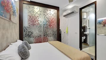 Une chambre à coucher comprenant un lit, une armoire avec des portes en verre décoratives, un appareil de climatisation et une salle de bain visible à travers une porte en verre.