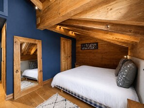 A bedroom with a wooden ceiling, a bed with white bedding, a blue wall, and a wooden door. - Comfortable apartment valley view - 10 guests (Saint-Martin-de-Belleville)