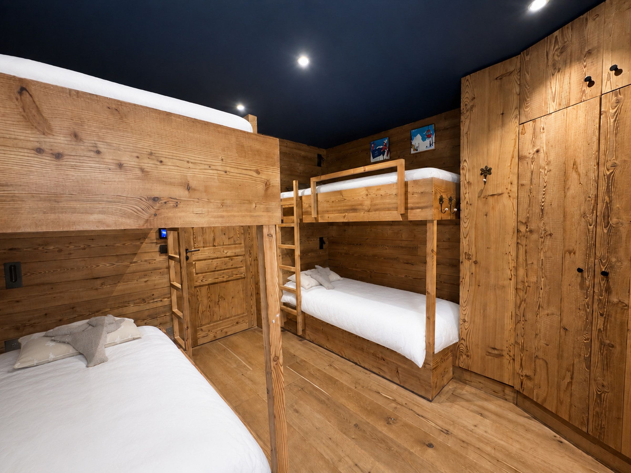 Une chambre avec un lit superposé en bois, une armoire et un petit bureau.