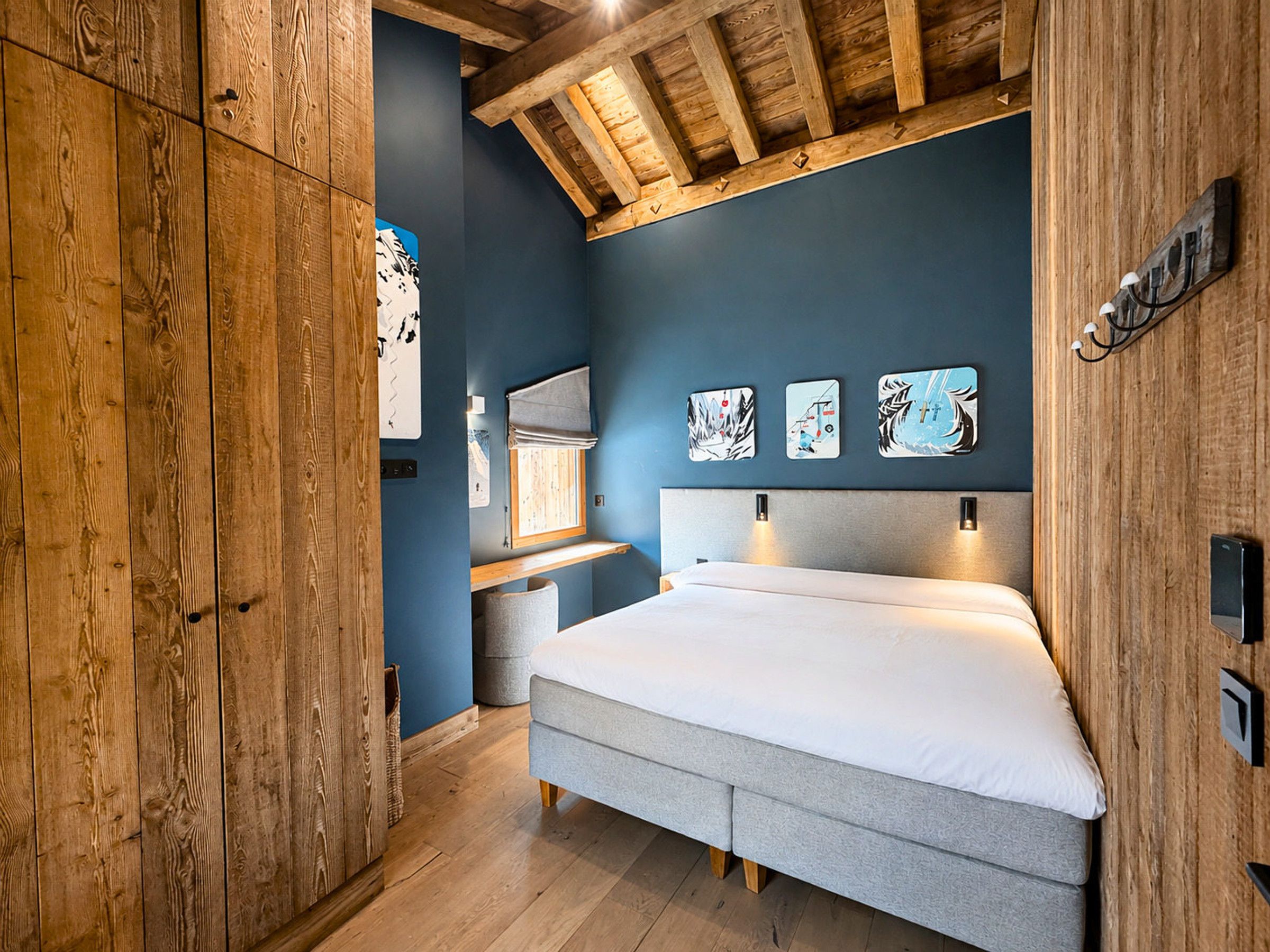 Une chambre à coucher avec un lit, des poutres en bois au plafond et des œuvres d’art accrochées au mur.