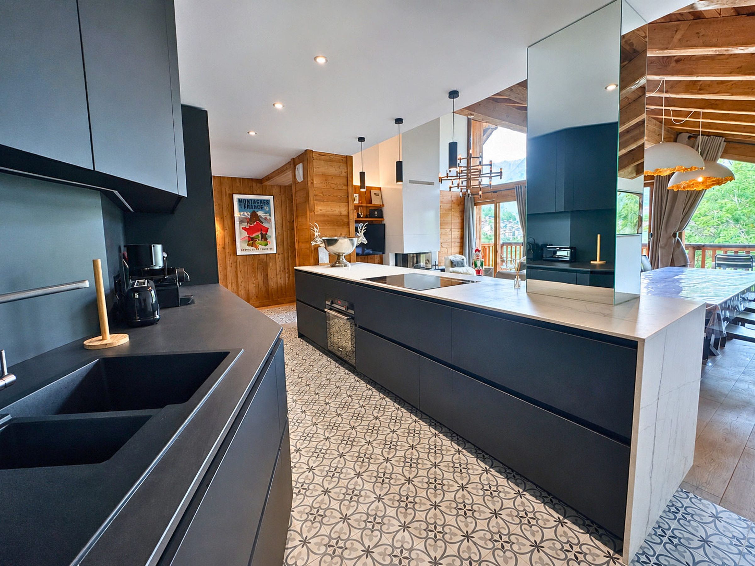 A modern kitchen with dark cabinetry, a large island, and a patterned floor.