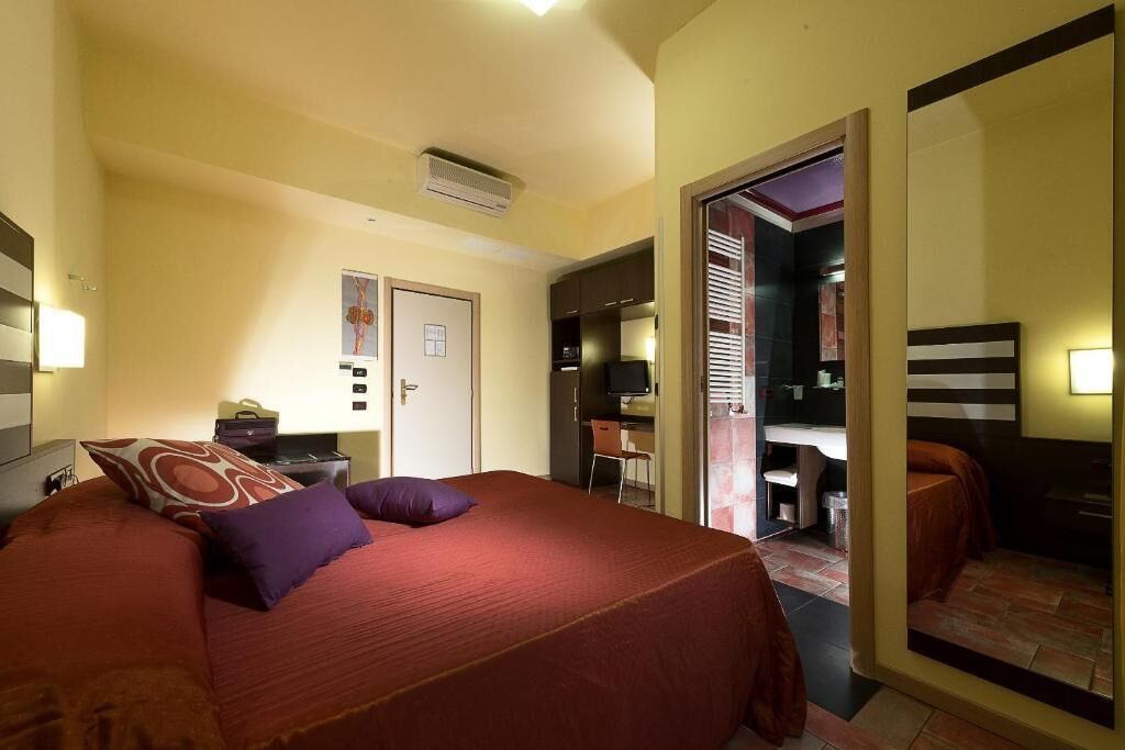 Habitació d'hotel amb un llit, una taula, una cadira i un mirall.