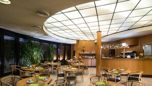 Un restaurant avec des tables rondes, des chaises et un coin bar.