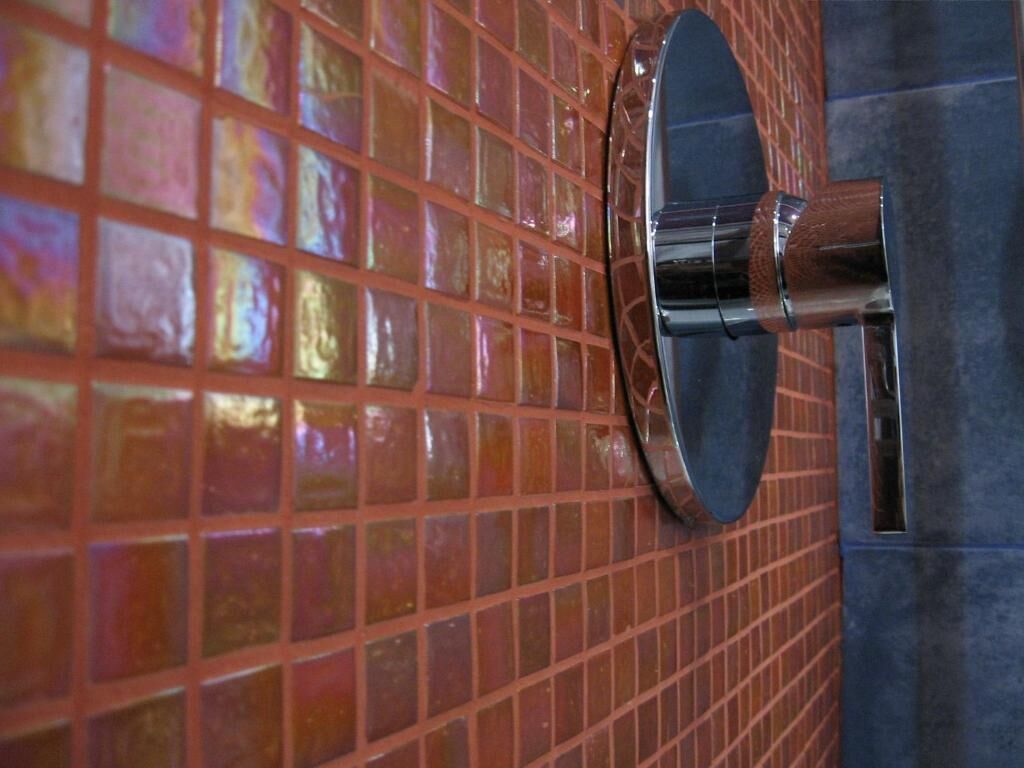 Un baño con pared de azulejos y grifo metálico.