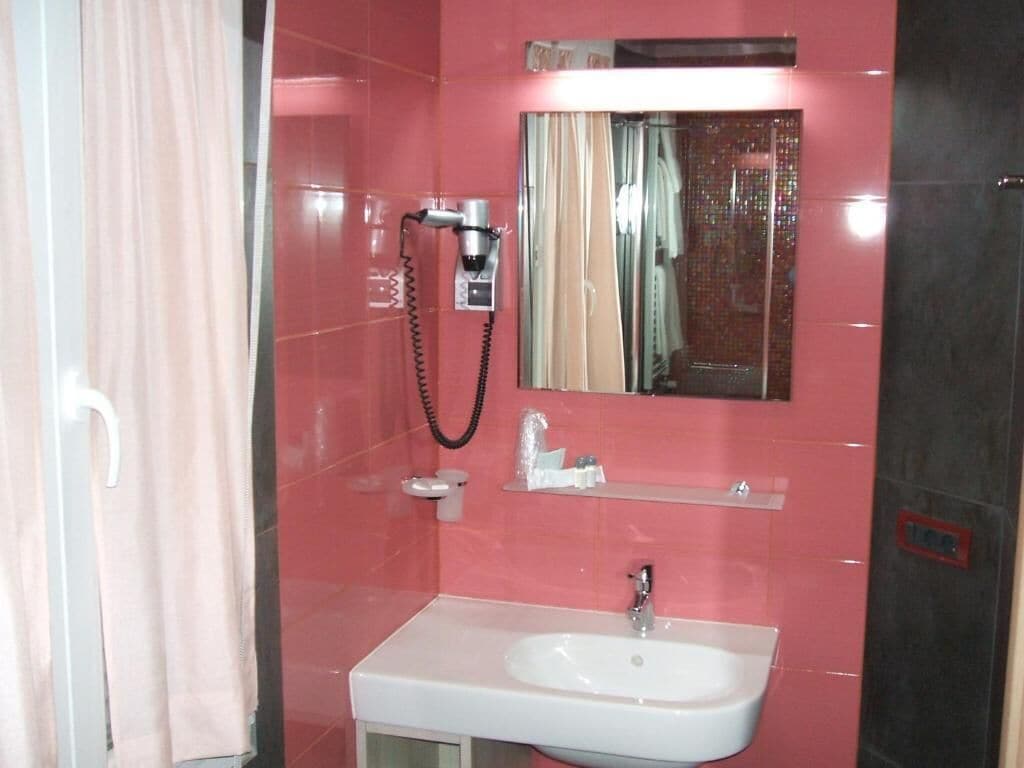 A bathroom with a white sink, a mirror, and a shower area.