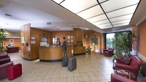 Un espace d’accueil d’hôtel comprenant un comptoir, des sièges et une grande fenêtre.
