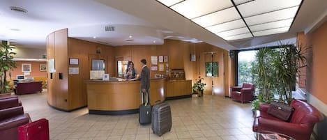 A hotel reception area with a counter, seating, and a large window.