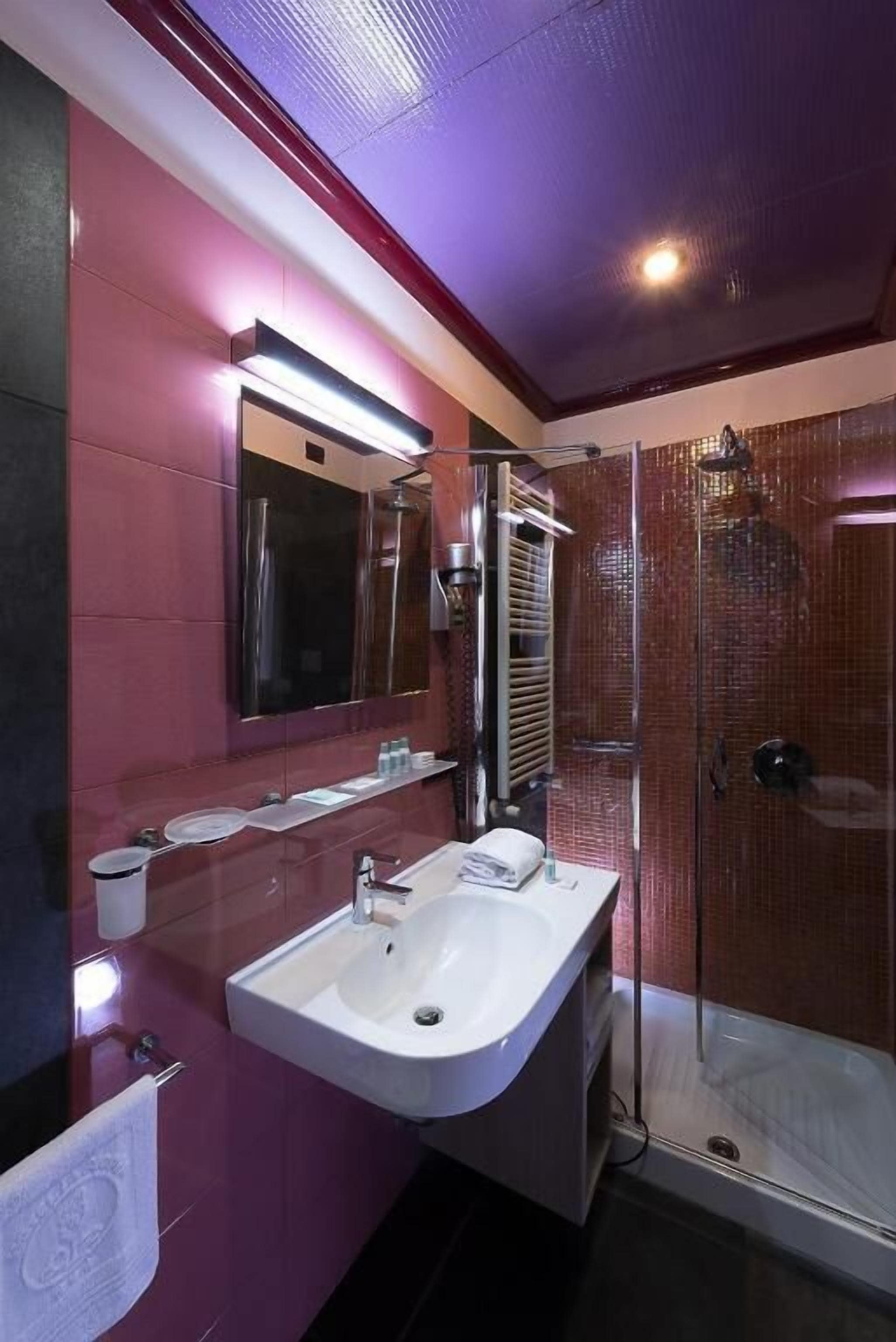 A modern bathroom with a glass shower enclosure, a large mirror, and a white sink.