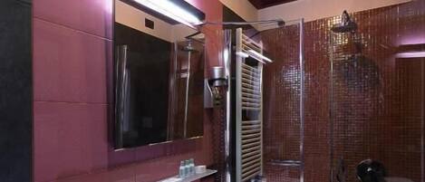 A modern bathroom with a glass shower enclosure, a large mirror, and a white sink.