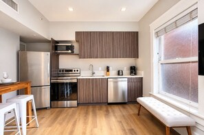 A modern kitchen with stainless steel appliances, wooden cabinets, and a bench by the window. - The Penn Hotel - Queen Bed, AC & Walk to Gaslamp!! (San Diego)