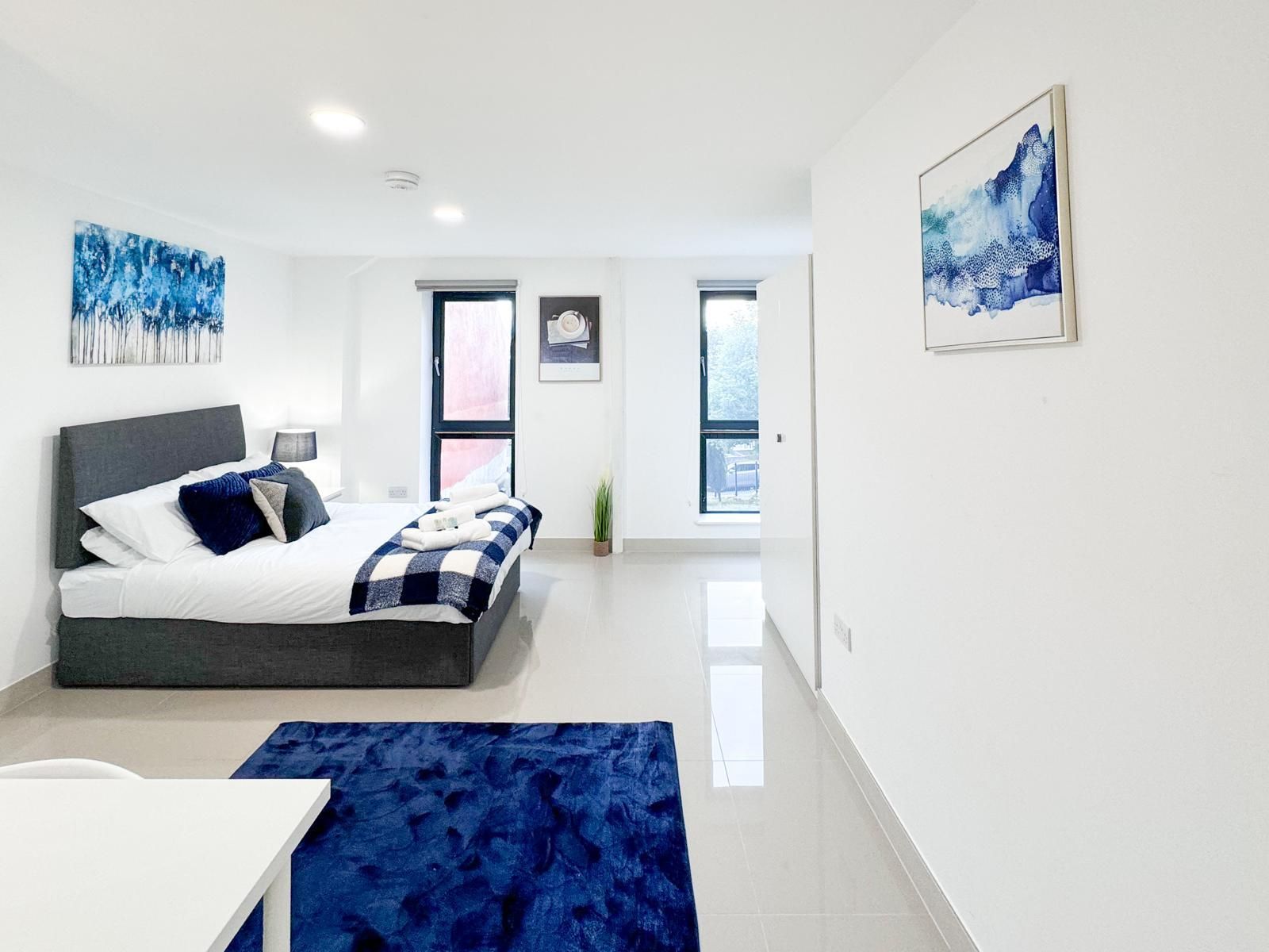 Une chambre à coucher moderne avec un lit, une table de chevet et une grande fenêtre.