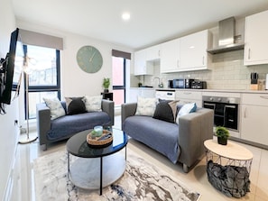 A modern living room with two sofas, a coffee table, and a kitchen area with white cabinets and appliances. - WeekdayDiscount | FreeParking | LastMinDeal | CityCentre - Pass the Keys (Leeds)
