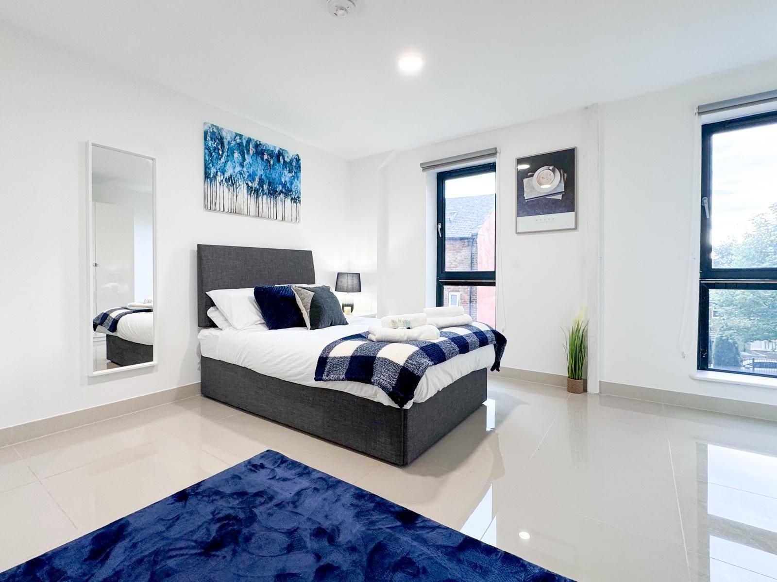 A modern bedroom with a large bed, a mirror, and a window.