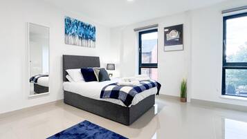 A modern bedroom with a large bed, a mirror, and a window.
