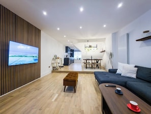 A modern living room with a flat-screen TV, a sofa, a coffee table, and a wooden floor. - Luxury 2 bed maisonette in Spitalfields zone 1 - Pass the Keys (London)