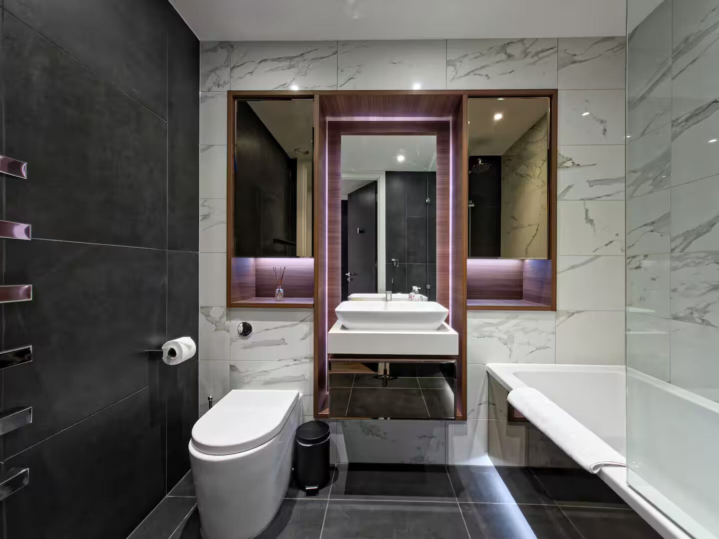 Ein modernes Badezimmer mit Toilette, Bidet und einem großen Spiegel über einem Waschbecken.