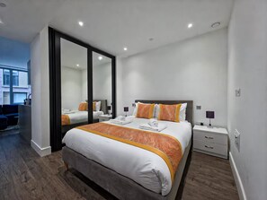Ein modernes Hotelzimmer mit einem großen Bett, Nachttischen und einem Spiegel.