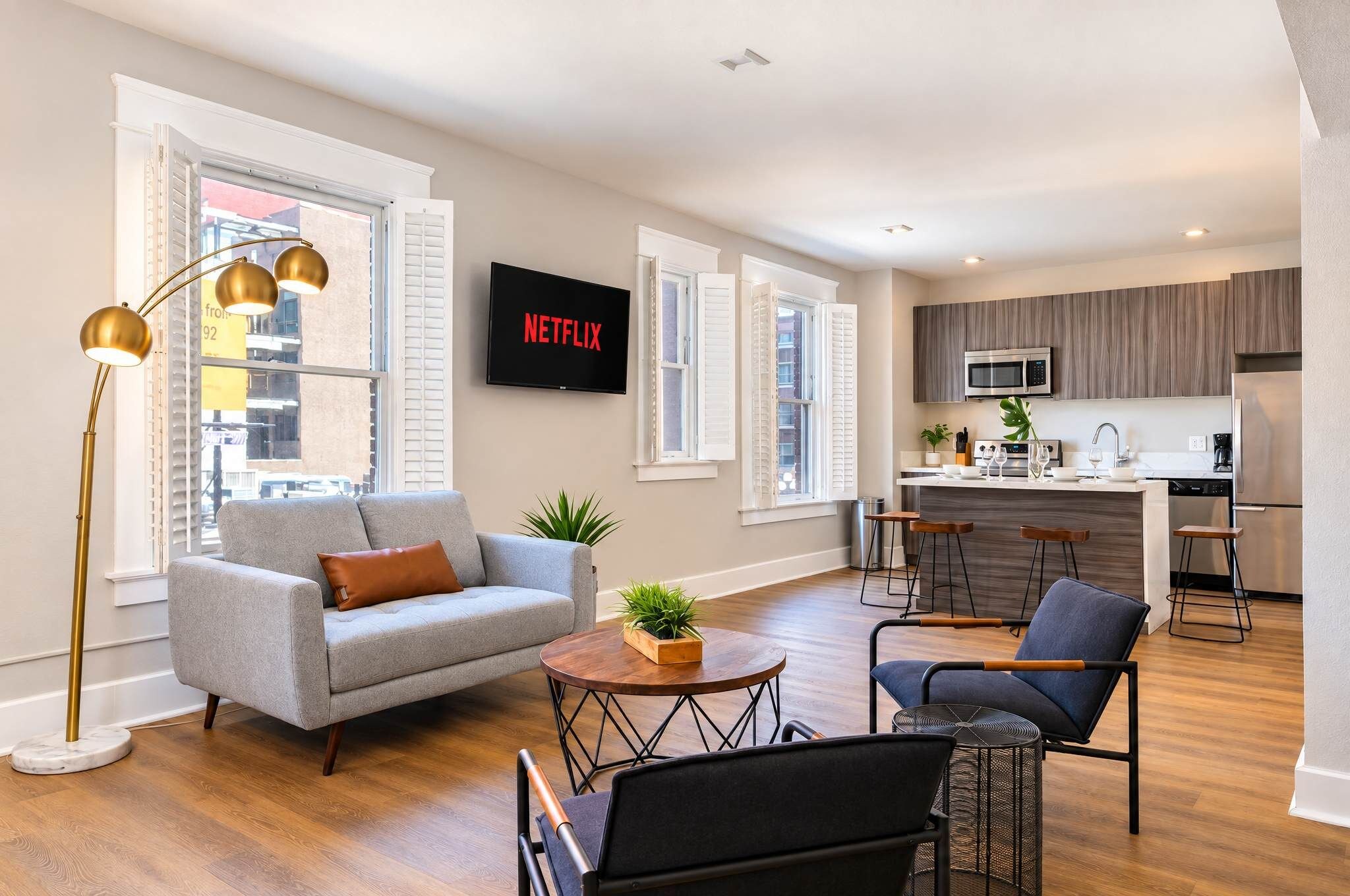 Una sala de estar moderna con un sofá gris, una mesa de centro y un televisor montado en la pared.