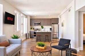 A modern living room with a grey sofa, a round coffee table with a plant, and a black chair. - The Penn Hotel - King Bed, AC & Gaslamp Nightlife! (San Diego)
