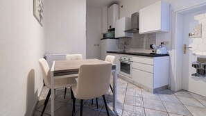 A modern kitchen with white cabinetry, a dining table with chairs, and a microwave. - Saragozza 76 (Bologna)