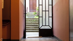 A hallway leading to a staircase with a decorative door. - Saragozza 76 (Bologna)