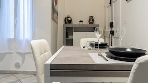 A modern dining area with a table set for two, including plates, cutlery, and glasses. - Saragozza 76 (Bologna)