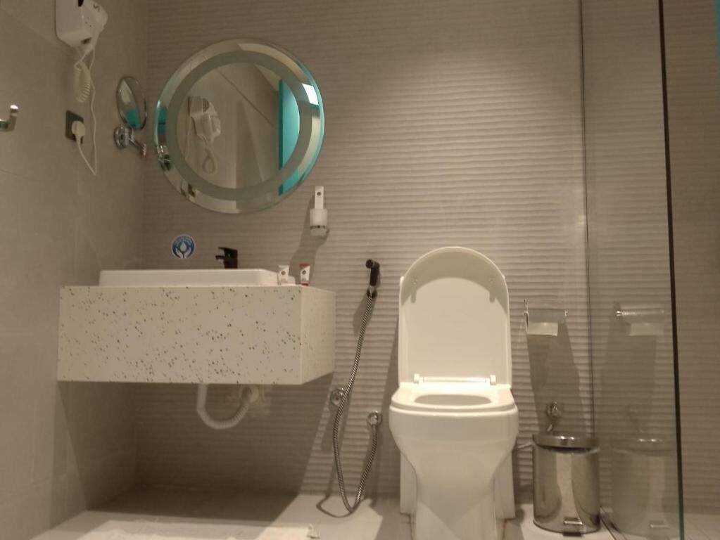 Un baño con inodoro, lavabo, espejo y ducha.